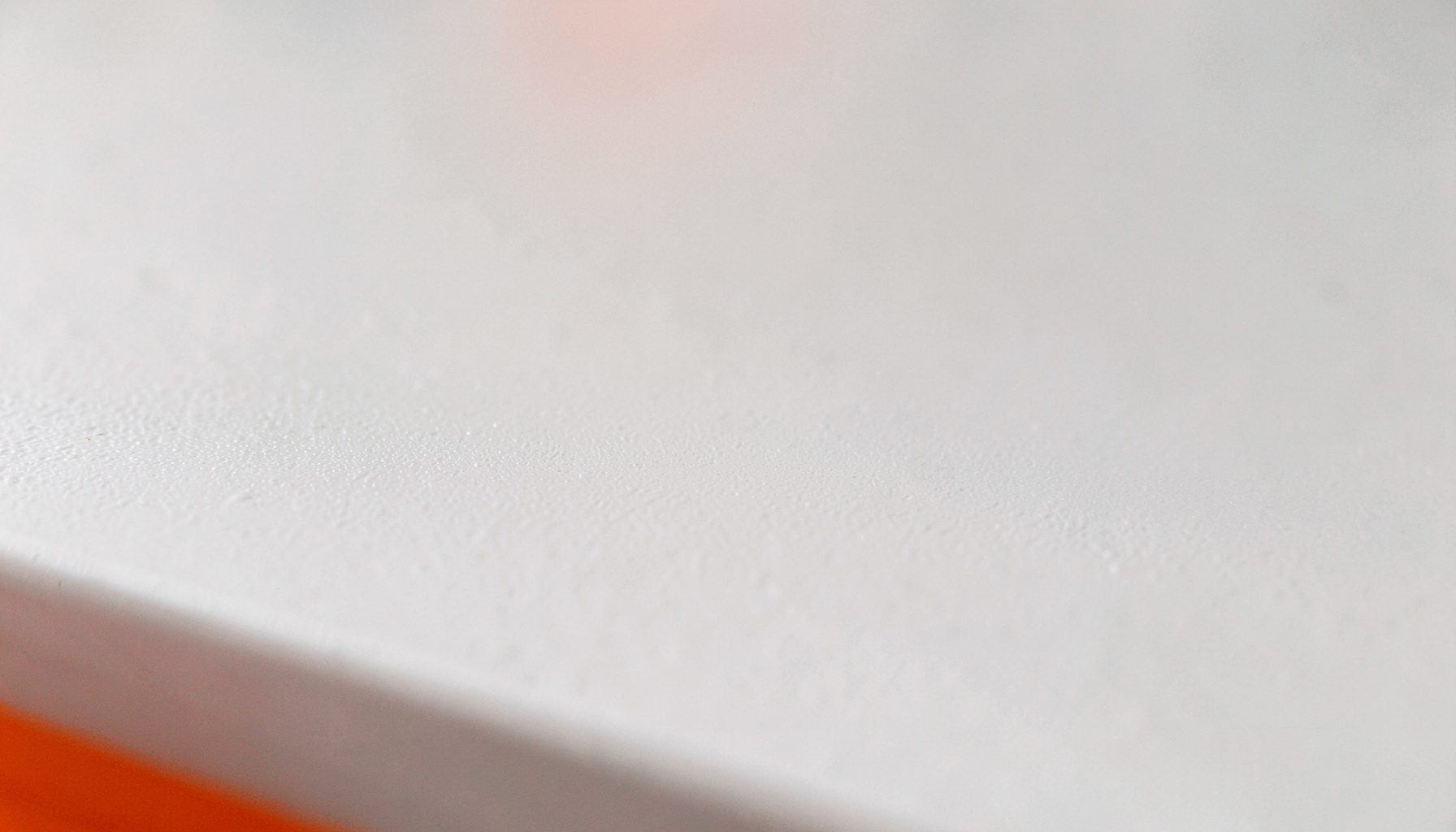 Extreme close-up photograph of a smooth matte laboratory bench surface in soft off-white and pale grey tones